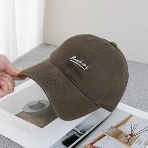 Detail of premium cotton baseball cap featuring white cursive Backing embroidery on brown
