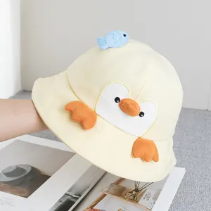 Detail of cute yellow penguin sun hat with 3D wings and a small fish doll on top