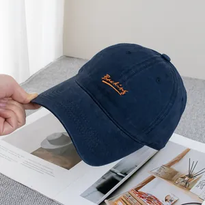 Detail of navy blue canvas baseball cap with orange Backing embroidery and reinforced stitching