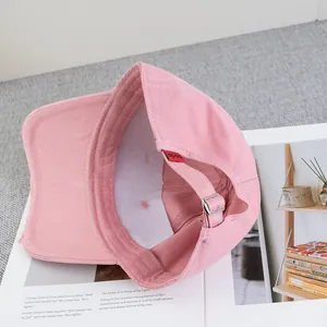 Detail of pink distressed baseball cap interior with metal buckle and logo label