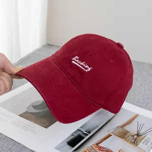Close-up of white Baching letter embroidery on a burgundy cotton baseball cap