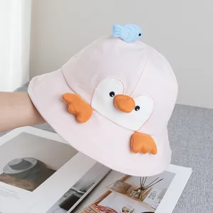Detail of pink cotton sun hat featuring embroidered penguin face and blue fish doll
