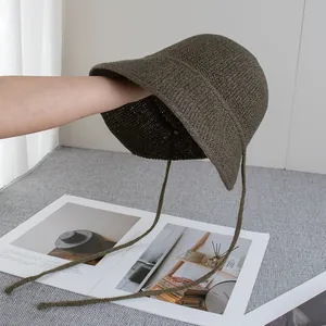 Dettaglio di un cappello pescatore vintage in paglia intrecciata con lacci verde scuro