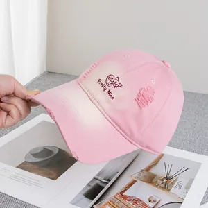 Detailed view of pink distressed baseball cap with cat embroidery and frayed brim