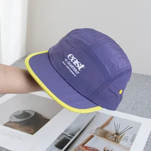 Detail of purple five-panel camper hat with yellow contrast trim and adventure embroidery