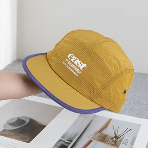 Detail of yellow ripstop fabric and purple brim on a 5-panel outdoor camping cap