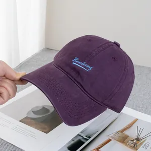 Close-up of deep purple cotton baseball cap featuring light blue Backing embroidery