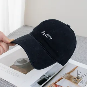 Close-up of white embroidered Backing text on a black cotton twill baseball cap