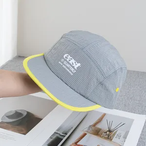 Close-up of grey ripstop baseball cap with yellow piping and white letter embroidery