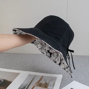 Detail view of double-sided sun hat featuring floral lining and black windproof strap