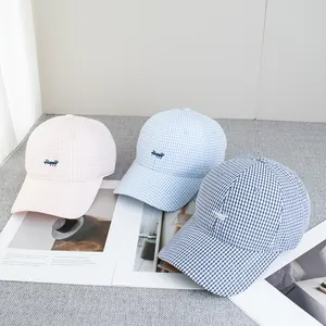 Tre cappellini a quadretti ricamati in rosa, azzurro e blu scuro disposti in piano