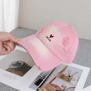 Detail of distressed pink gradient baseball cap with embroidered heart and HELLO logo