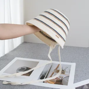 Detail of beige striped knit bucket hat featuring fine texture and adjustable ties