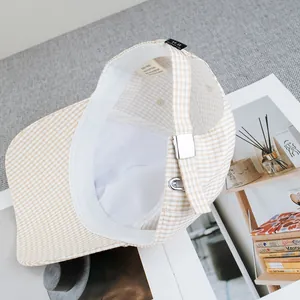 Dettaglio della fodera bianca e fibbia in metallo argentato di un cappello beige a scacchi