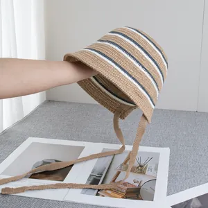 Macro detail of khaki straw bucket hat featuring blue and white stripes and woven ties