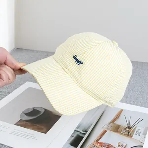 Dettaglio del cappellino a quadretti gialli con scritta ricamata Happy blu
