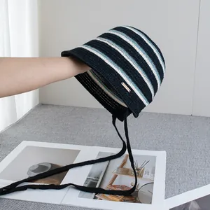 Close-up of striped knit bucket hat featuring a metal logo tag and long woven drawstrings