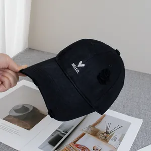 Close-up of black distressed baseball cap with white Hello and heart embroidery detail