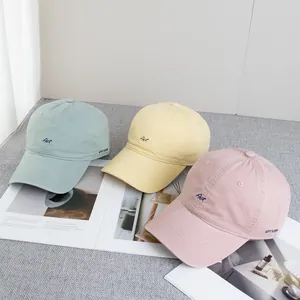 Detail of embroidered Art logo on three pastel cotton baseball caps in macaron colors