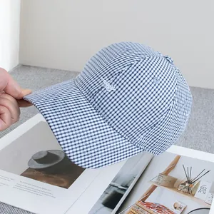 Dettaglio del ricamo su cappellino vichy blu e bianco con morbida trama di cotone