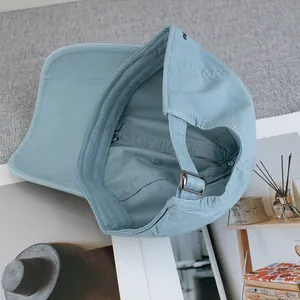 Detailed view of inner stitching and adjustable metal buckle on light blue baseball cap