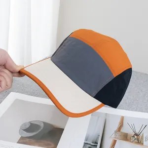 Detail einer 5-Panel-Camper-Mütze mit orangefarbenem Rand und verstärktem Schirm
