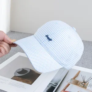 Dettaglio del cappellino a quadretti blu e bianchi con ricamo Happy su rivista aperta