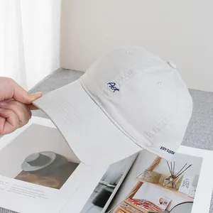 Detailed close-up of navy 'Art' embroidery on a light beige cotton baseball cap