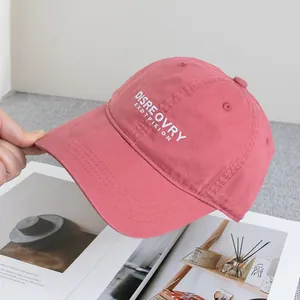 Close-up of pink cotton baseball cap with white embroidery and reinforced brim stitching