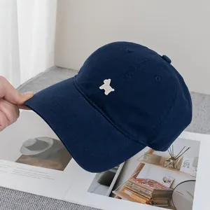 Detail der weißen Welpenstickerei auf einer marineblauen Baumwoll-Baseballkappe in Lifestyle-Ansicht