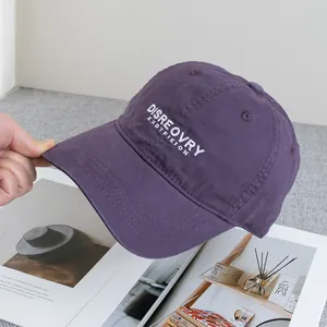 Detail of purple cotton baseball cap featuring white letter embroidery and washed texture