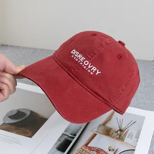 Detailed close-up of brick red washed cotton baseball cap with white letter embroidery