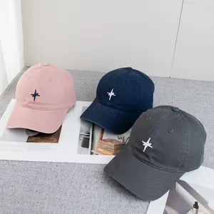 Trois casquettes brodées d'étoiles en rose, marine et gris sur un magazine de mode