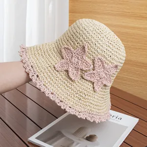 Close-up of handmade straw hat with pink crochet stars and scalloped lace brim details