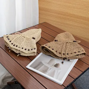 Dettaglio della trama di cappelli di paglia intrecciati a mano con perle e fiocchi