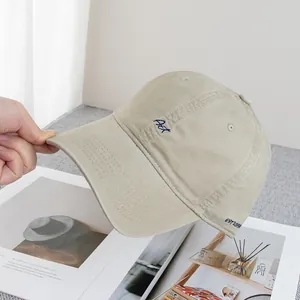Detailed embroidery of blue Art lettering on a beige cotton baseball cap with soft texture