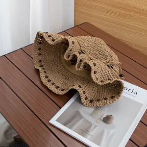 Dettaglio di un cappello di paglia intrecciato a mano con texture traforata e perline