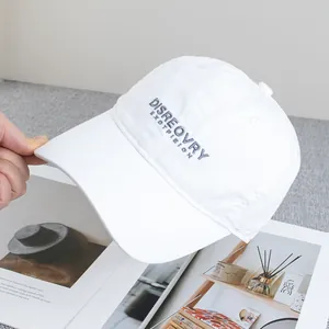 Detail of white cotton baseball cap with dark letter embroidery and curved brim design