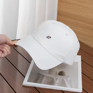Dettaglio del cappellino bianco con ricamo della lettera S marrone e cuciture di qualità