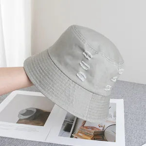 Gros plan détaillé sur les finitions déchirées d'un chapeau bob en toile gris clair