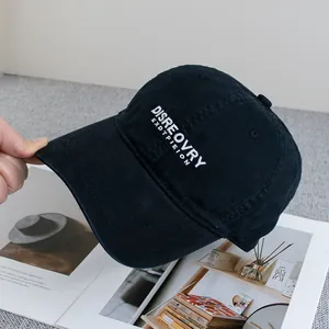 Close-up of white letter embroidery on a washed black cotton baseball cap