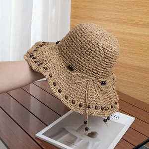 Dettaglio di cappello in paglia intrecciato a mano con perline di legno e fiocco