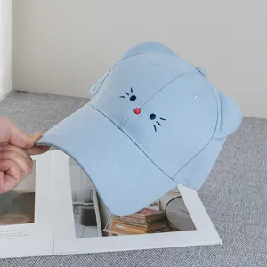 Dettaglio del cappellino azzurro con orecchie di gatto 3D e ricamo viso di animale