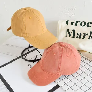 Detail von gewaschenen Baumwoll-Baseballkappen in Ingwer und Ziegelrot mit Retro-Textur