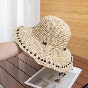 Dettaglio del cappello di paglia fatto a mano con perle decorative in legno marrone scuro