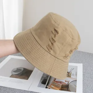 Détail du bob en coton kaki avec tissu déchiré et coutures de renforcement sur le bord