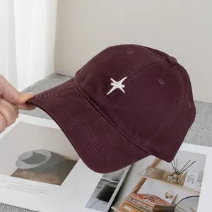 Gros plan d'une casquette bordeaux avec broderie étoile blanche et coutures soignées