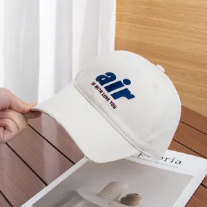 Detailed view of cream cotton baseball cap with blue air embroidery and distressed brim