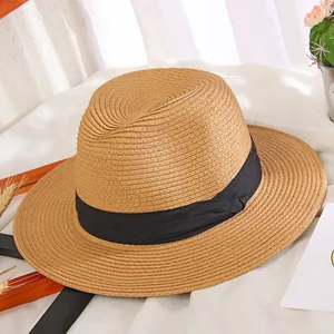Classic straw sun hat with black ribbon band on minimalist white fabric background