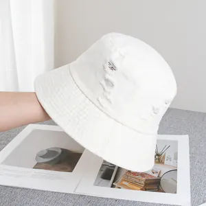 Gros plan sur le chapeau bob en coton crème avec trous déchirés et détails effilochés